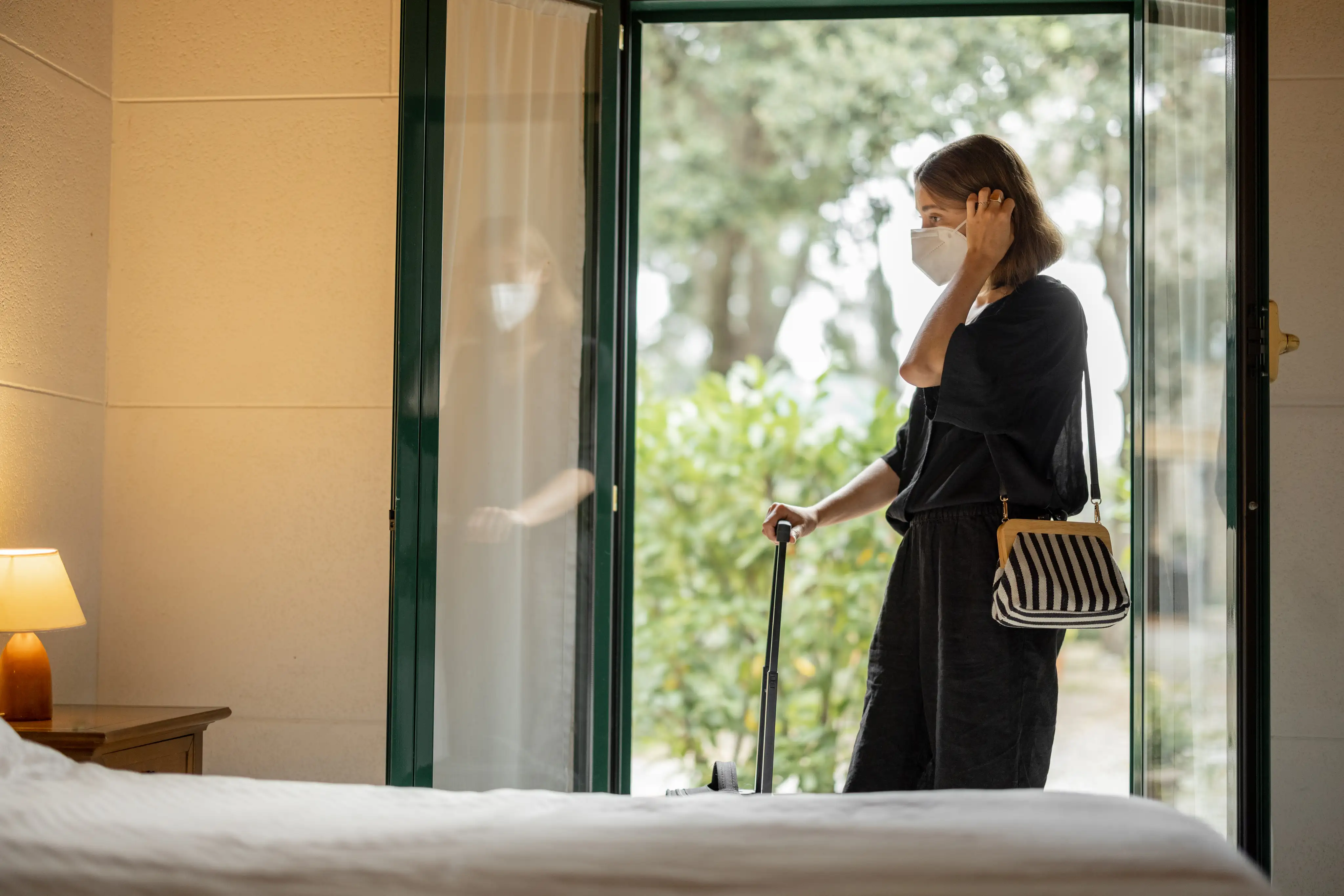 woman in medical mask entering in hotel room 2021 12 10 01 50 34 utc