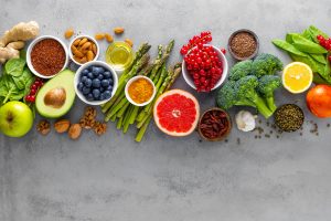 Healthy food background, spinach, quinoa, apple, blueberry, asparagus, turmeric, red currant, broccoli, mung bean, walnuts, grapefruit, ginger, avocado, almond, lemon, green peas and goji, top view